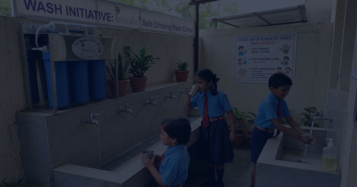 School children drinking safe water from a Parashu® filtration system installed under a WASH project
